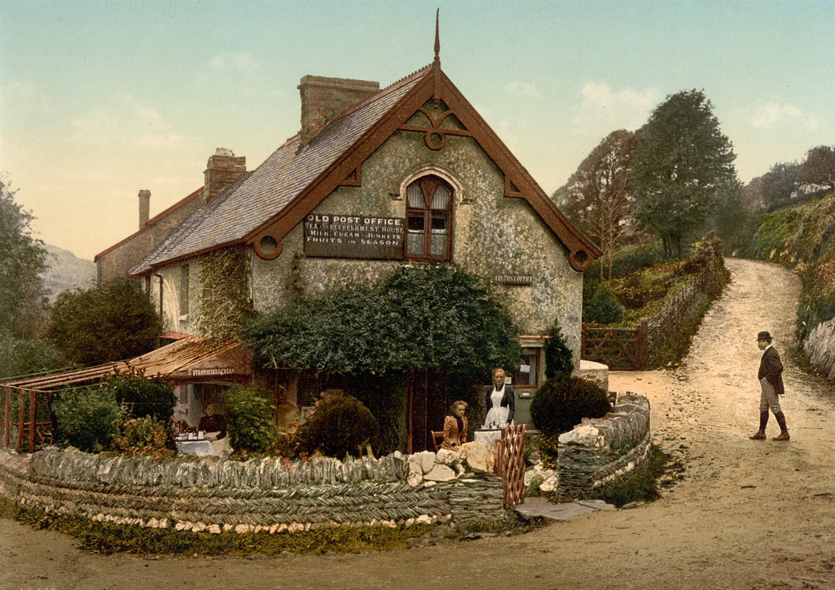 Ivy-covered village post office beside a winding lane with figures and stone walls.