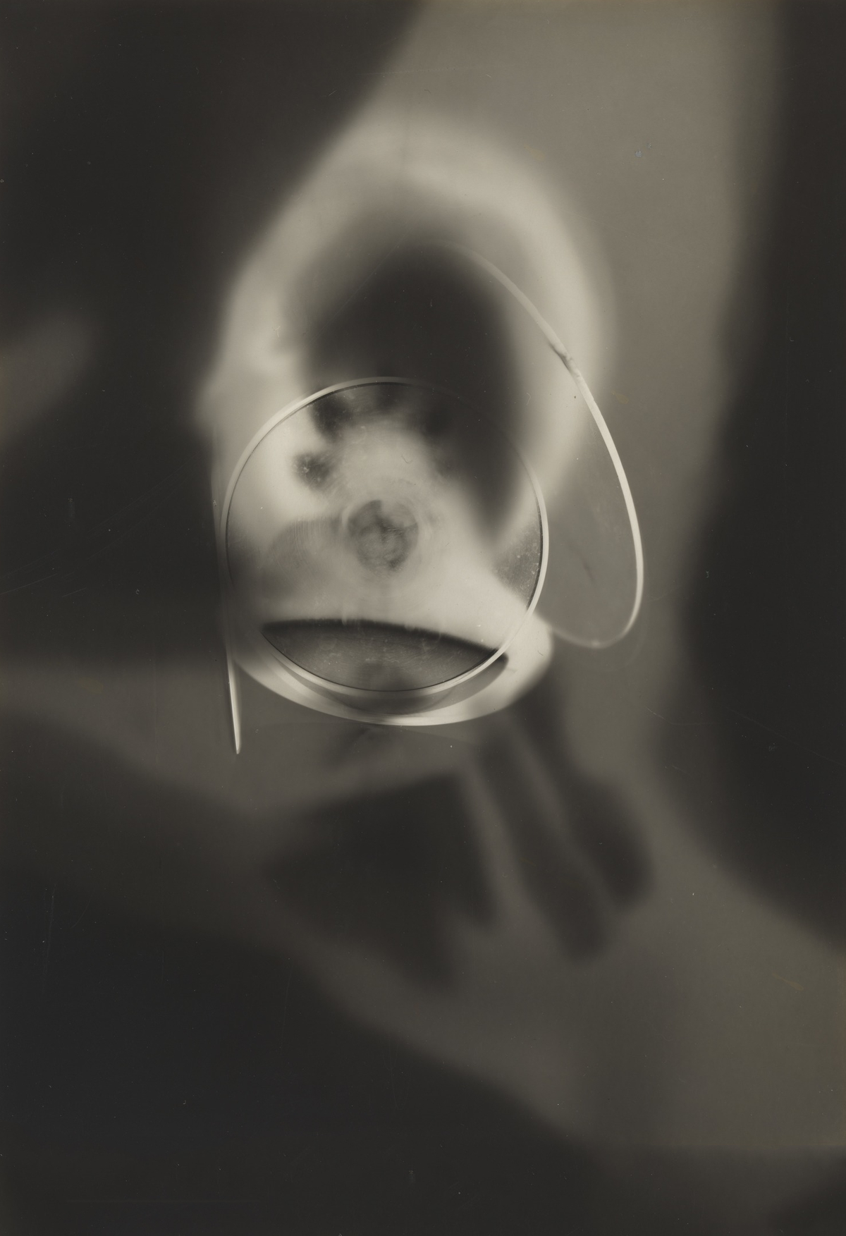 Looping wire-like curves cross a softly glowing circular form against a dark, hazy background.