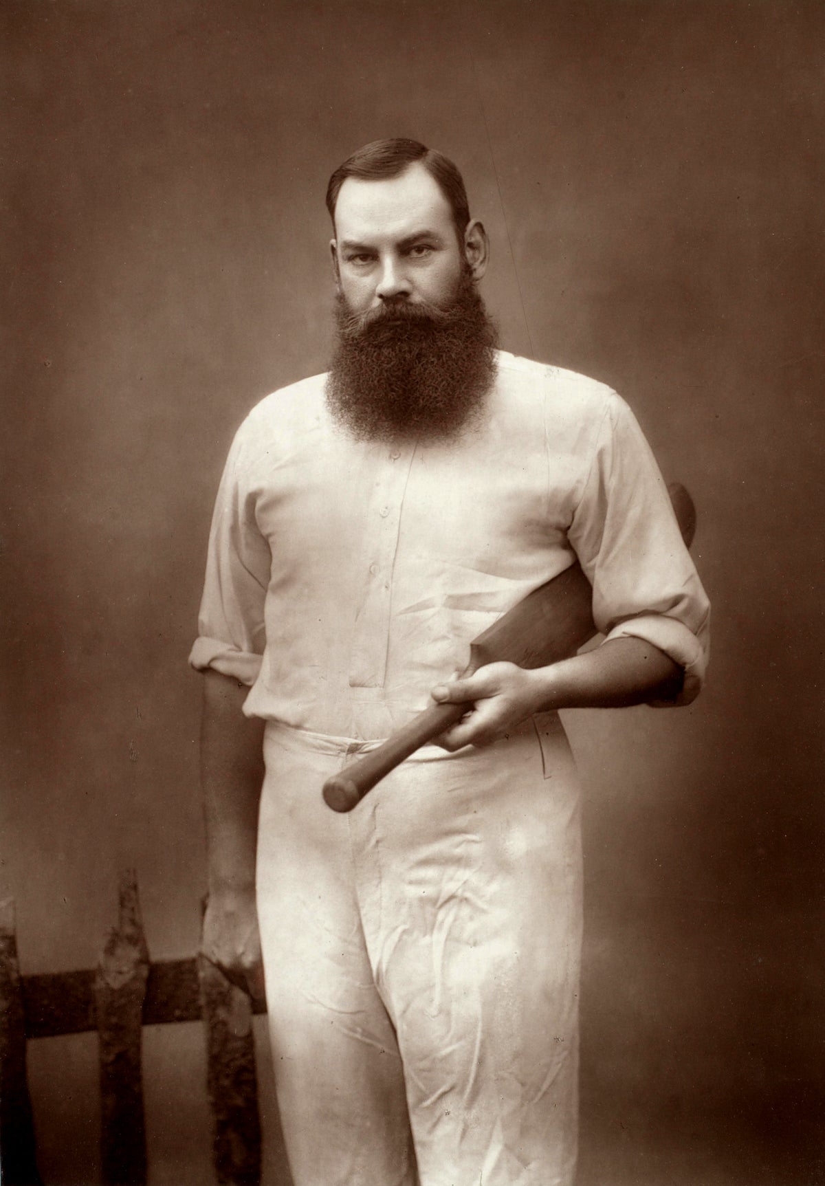 A sepia-toned photographic portrait of W. G. Grace in cricket whites, holding a bat.