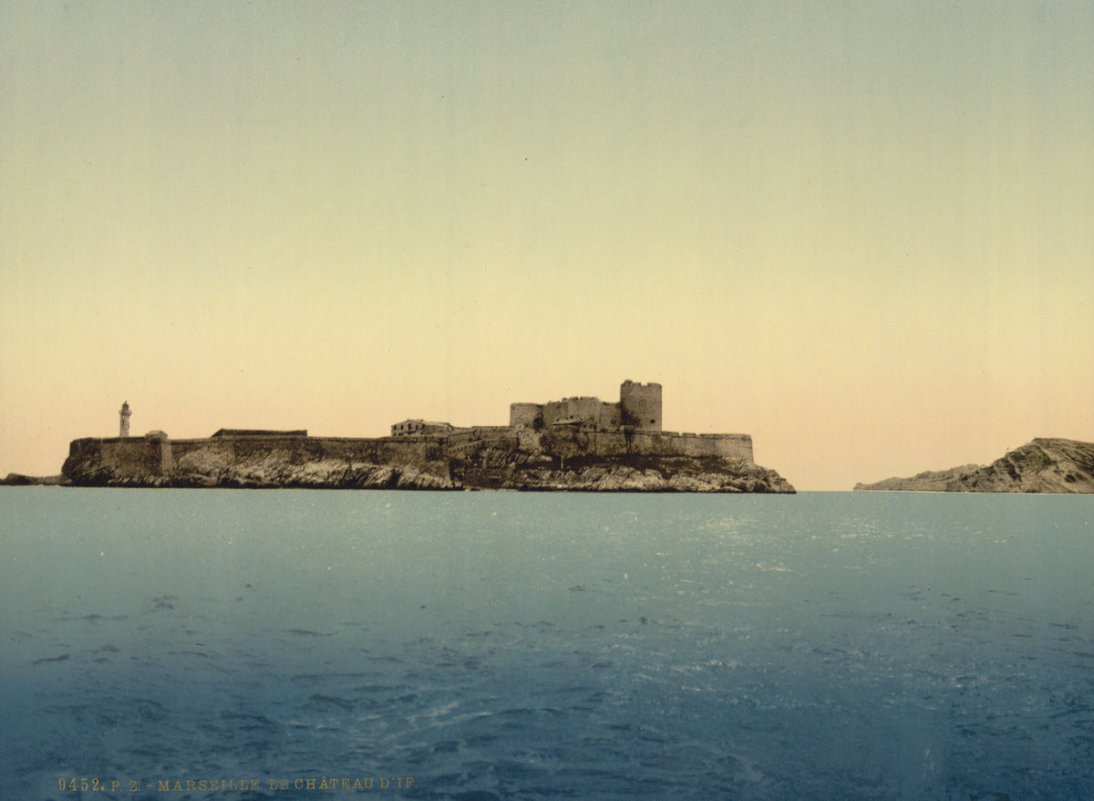 The island fortress of Chateau d'If stretches across the horizon above calm blue water in a softly coloured historic coastal view.