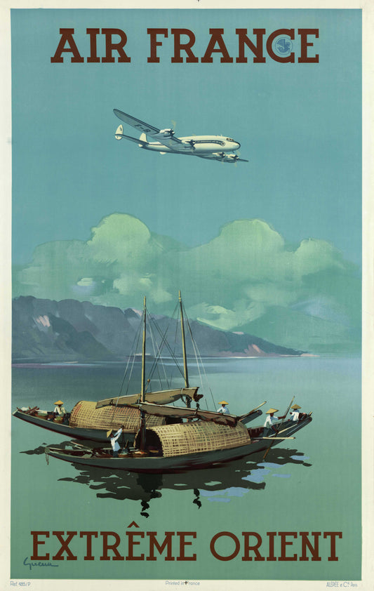 A silver airliner crosses a pale turquoise sky above traditional boats, calm water and distant green mountains.