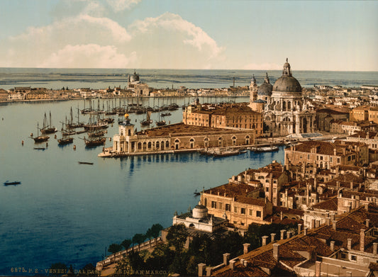 An elevated view takes in Venice’s domed waterfront churches, terracotta rooftops and sailing vessels across a pale blue lagoon.