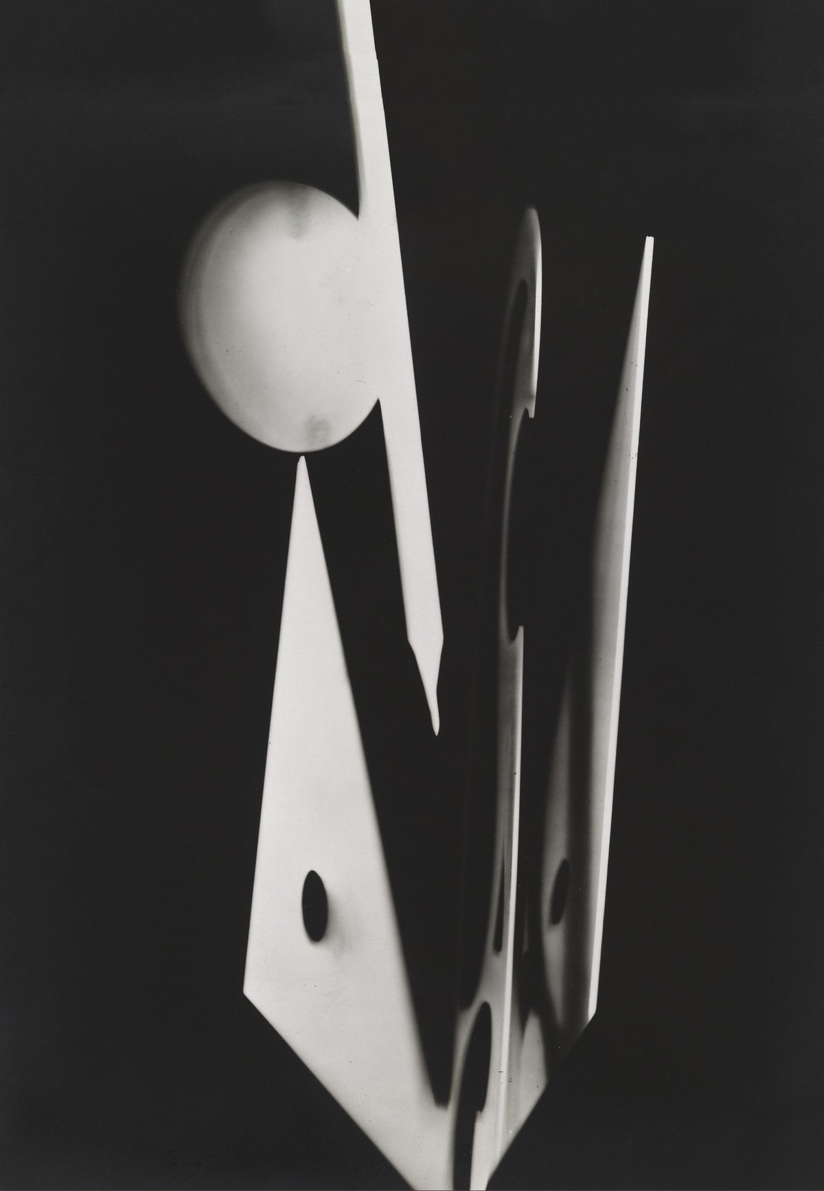 Long narrow white forms, a pale circle and an angular cut-out shape create a striking vertical abstract composition.