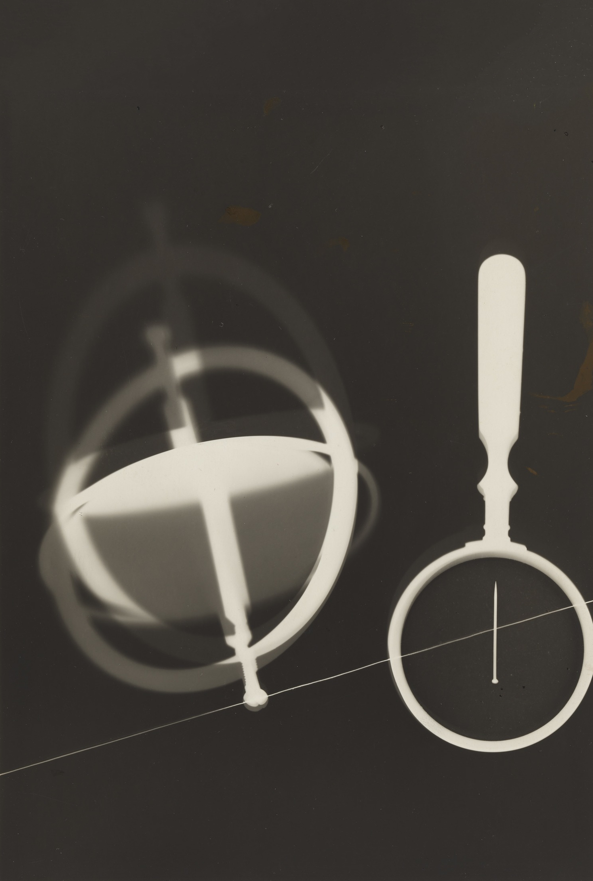 Two circular instrument-like forms, a vertical handle and a fine diagonal line create a spare black-and-white composition.